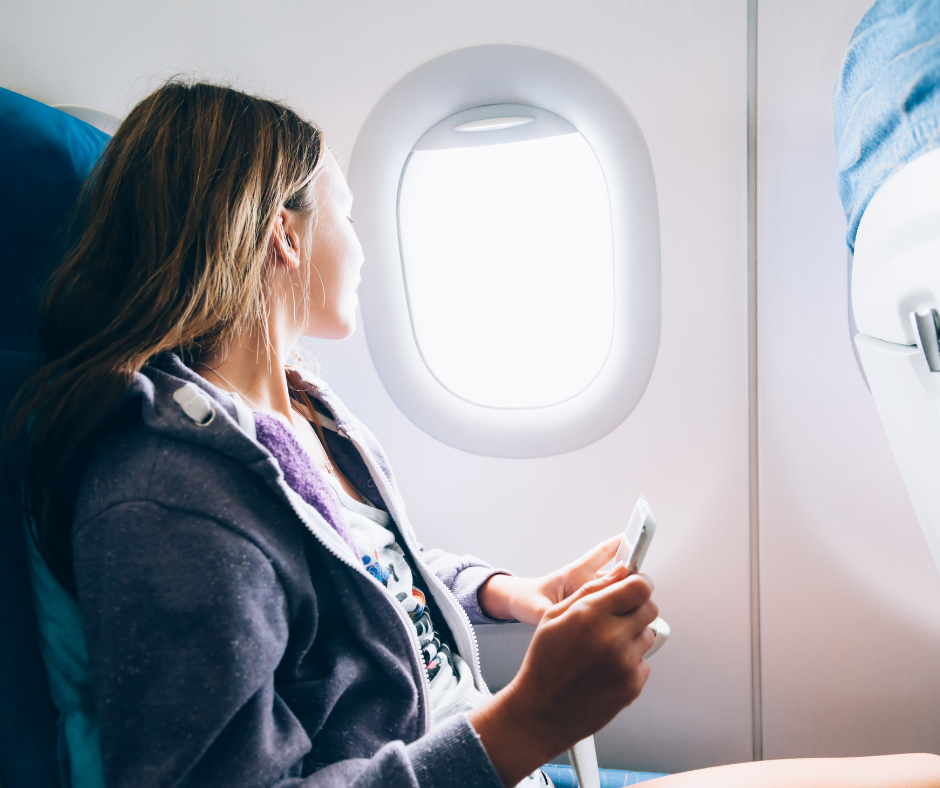 Passenger gazing out of a plane window, opting for non-alcoholic alternatives while flying