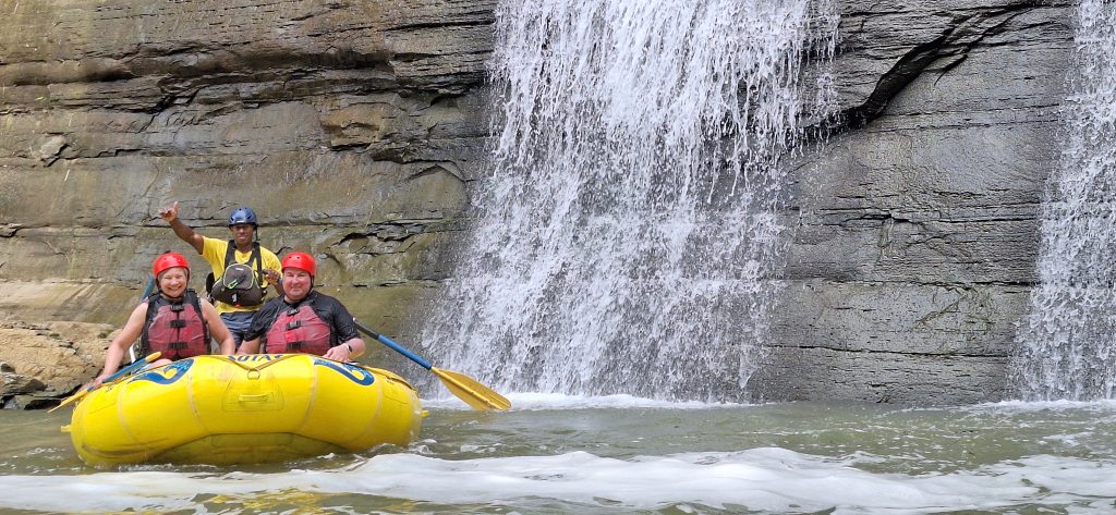 Under a cascading waterfall during the Upper Navua River Rafting adventure in Fiji, guided by Rivers Fiji