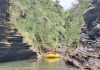 Rafting group navigating through a narrow volcanic gorge on the Upper Navua River, surrounded by rugged rock formations and lush greenery in Fiji.