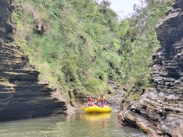 Rafting group navigating through a narrow volcanic gorge on the Upper Navua River, surrounded by rugged rock formations and lush greenery in Fiji.