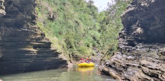 Rafting group navigating through a narrow volcanic gorge on the Upper Navua River, surrounded by rugged rock formations and lush greenery in Fiji.