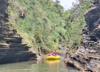 Rafting group navigating through a narrow volcanic gorge on the Upper Navua River, surrounded by rugged rock formations and lush greenery in Fiji.