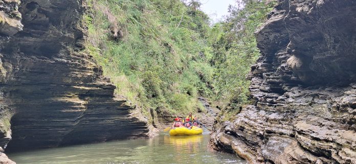 Rafting group navigating through a narrow volcanic gorge on the Upper Navua River, surrounded by rugged rock formations and lush greenery in Fiji.